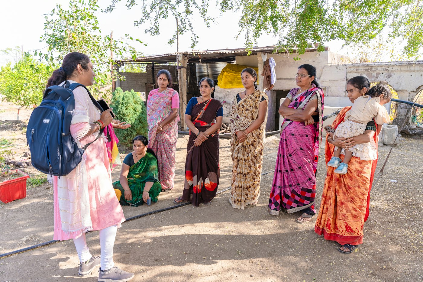 A field officer talking with a group of women outside their homes in a village